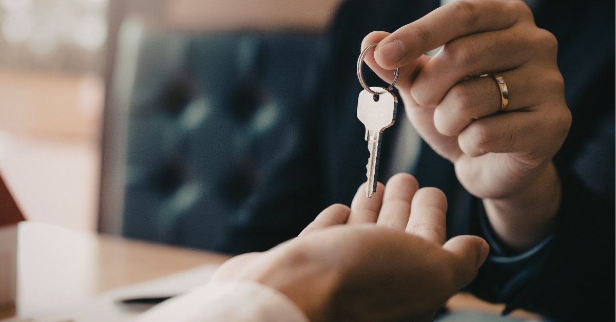 A person handing over a key to another person