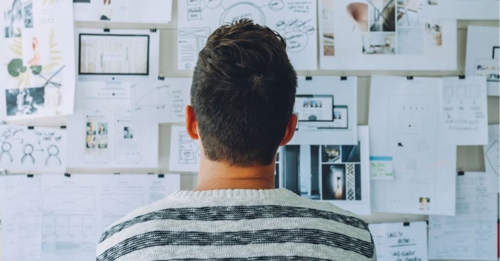 Man looking at wall of papers