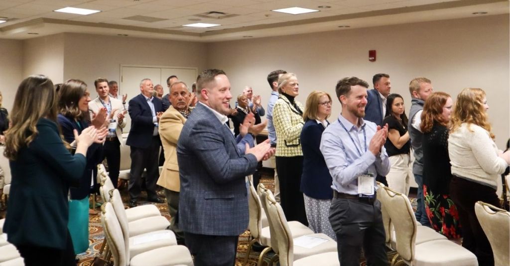 Go Big attendees smiling and clapping for an award recipient