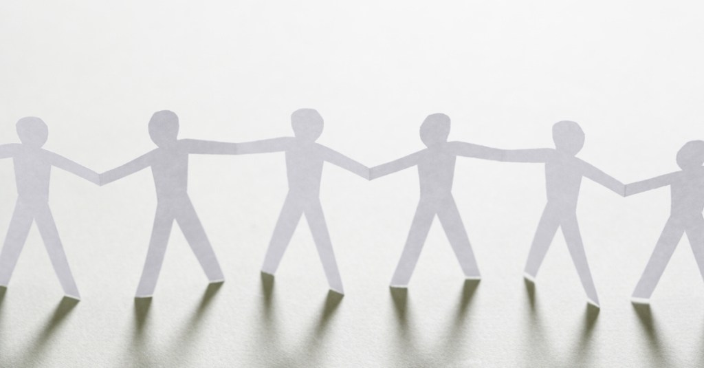 Paper cutouts of people figures connected and holding hands