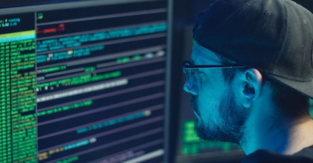 A man looking at a computer screen of code sequences