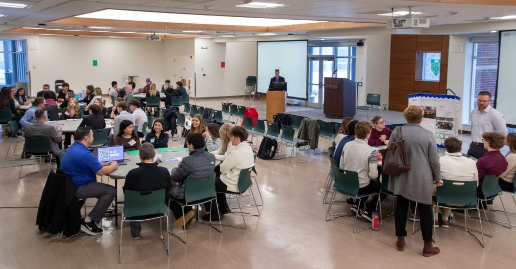 Wide shot view of room full of people at the Invest Field Trip 2025 at LeMoyne College