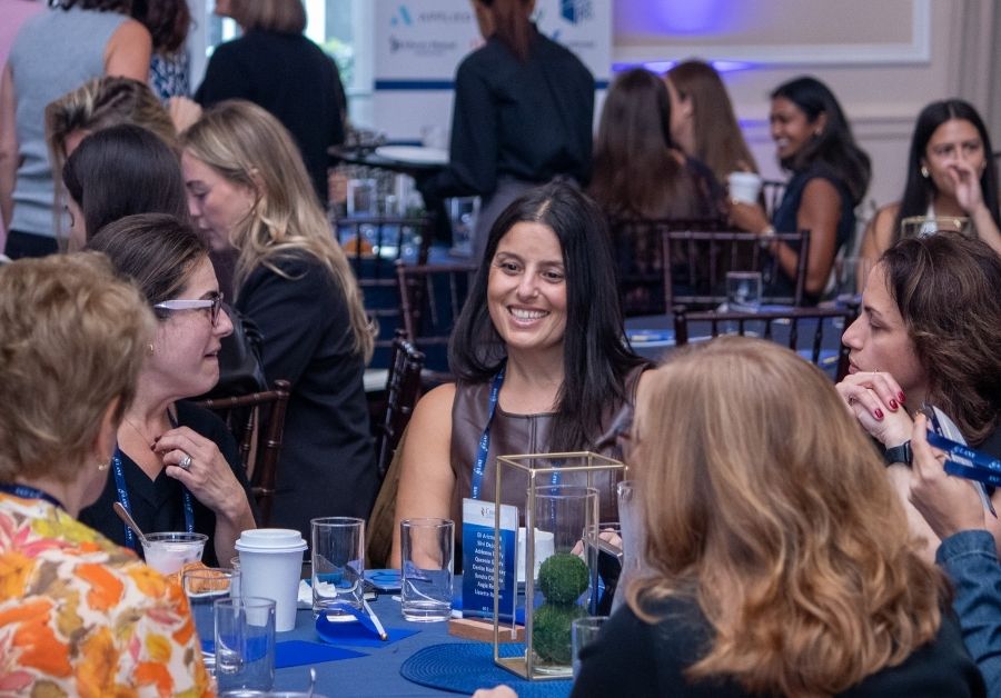 Woman smiling at a table at the Big I NY Women in Insurance 2026.