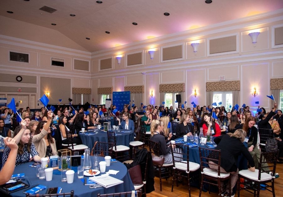 Wide shot view of the crowd waving blue flags at the Big I NY Women in Insurance 2026.
