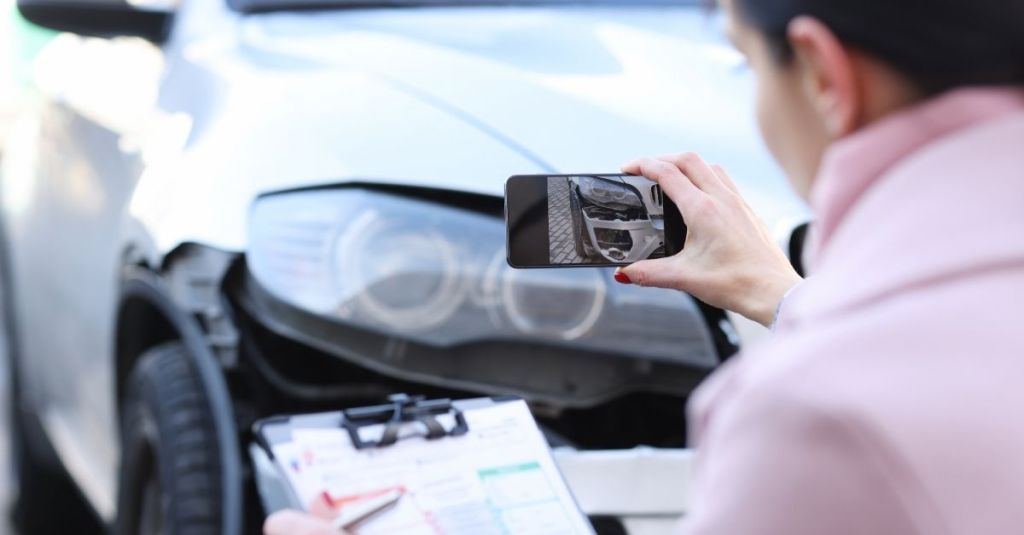 Woman taking a picture of damage to a car