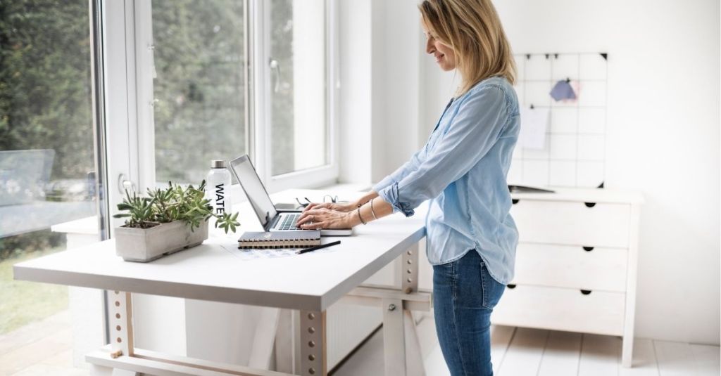 Woman working on a laptop at a standing desk