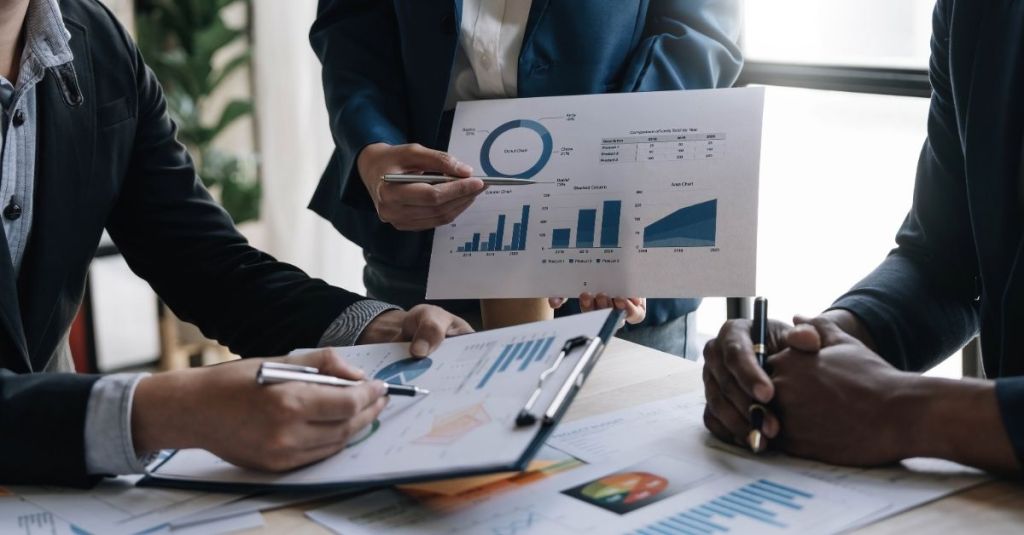Three people looking over charts and graphs