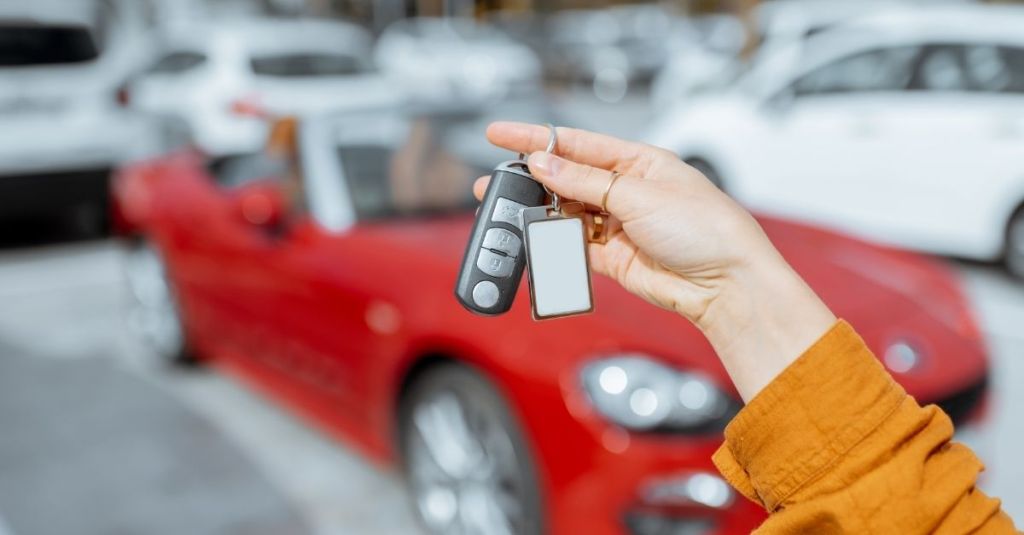 Person holding car keys in front of a red car