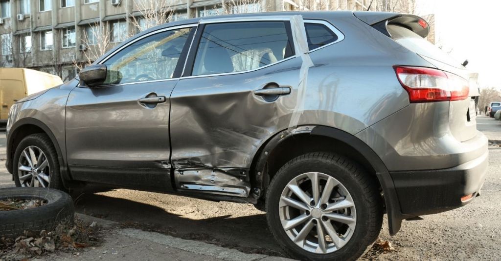 Grey SUV with a large dent on the left backseat passengers side