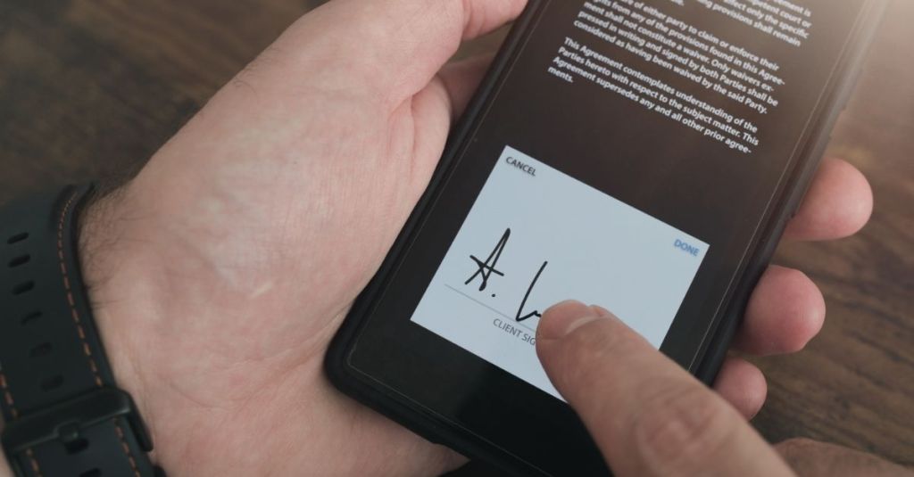 Person drawing their signature on a phone screen