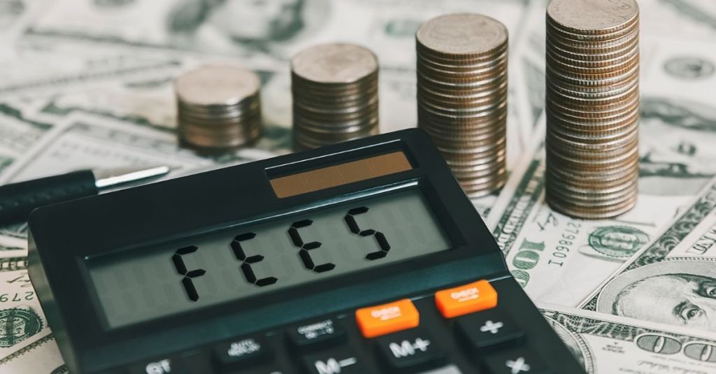 The word 'fees' typed out into a calculator with money in the background