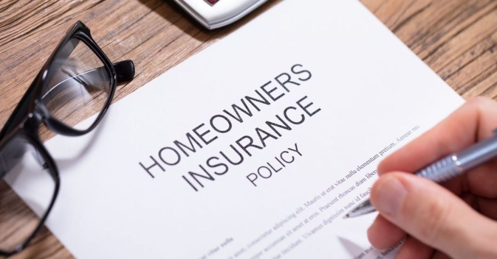Person writing on a homeowners policy document