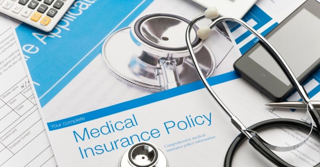 Medical insurance policy documents beside a stethoscope
