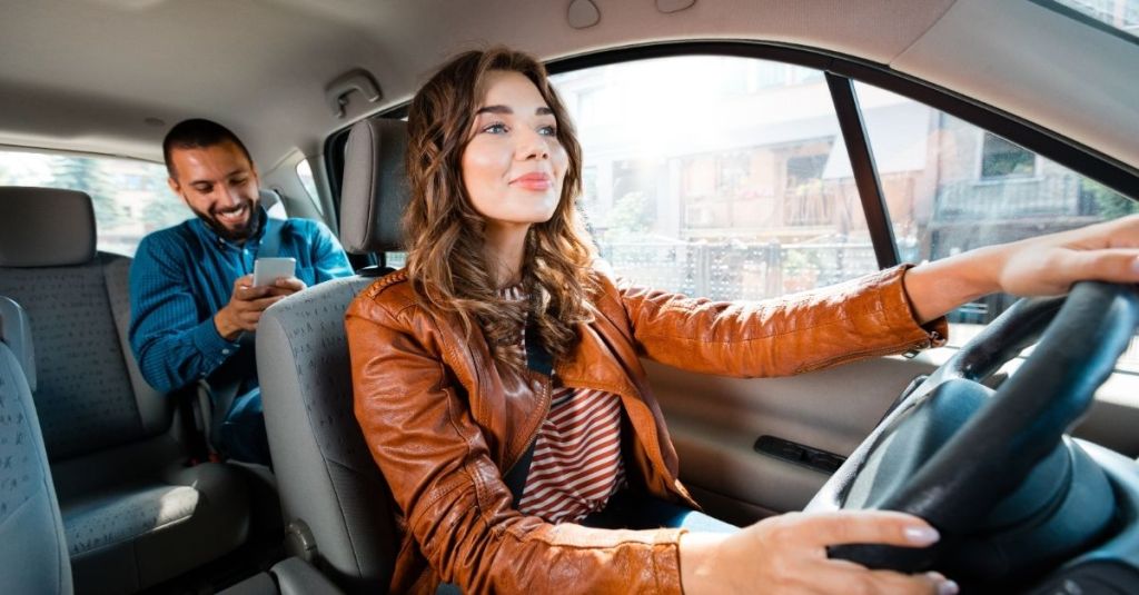 Woman driving with a male passenger in the backseat