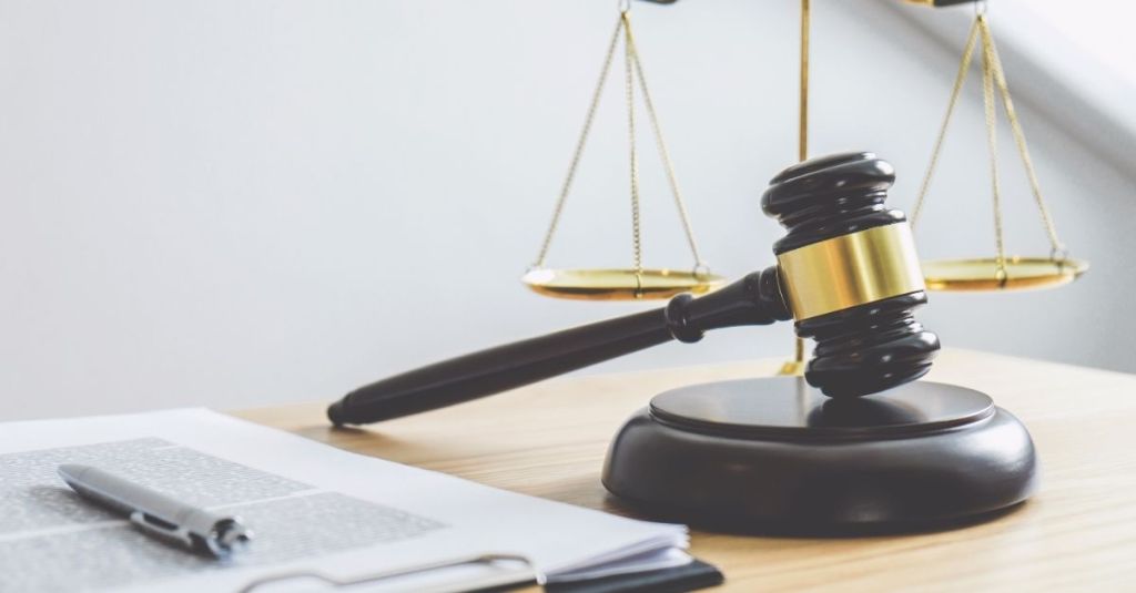 Gavel and scale of justice stand beside a clipboard