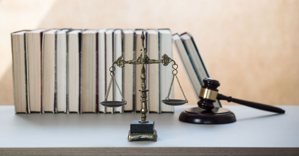 A weighing scale and gavel in front of a row of books