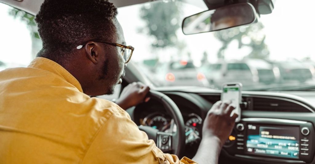 Rideshare driver tapping on phone while in the driver's seat