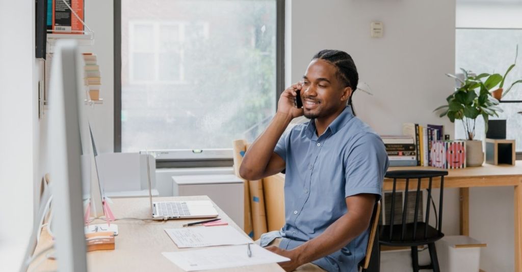 Man sitting at computer desk while talking on the phone