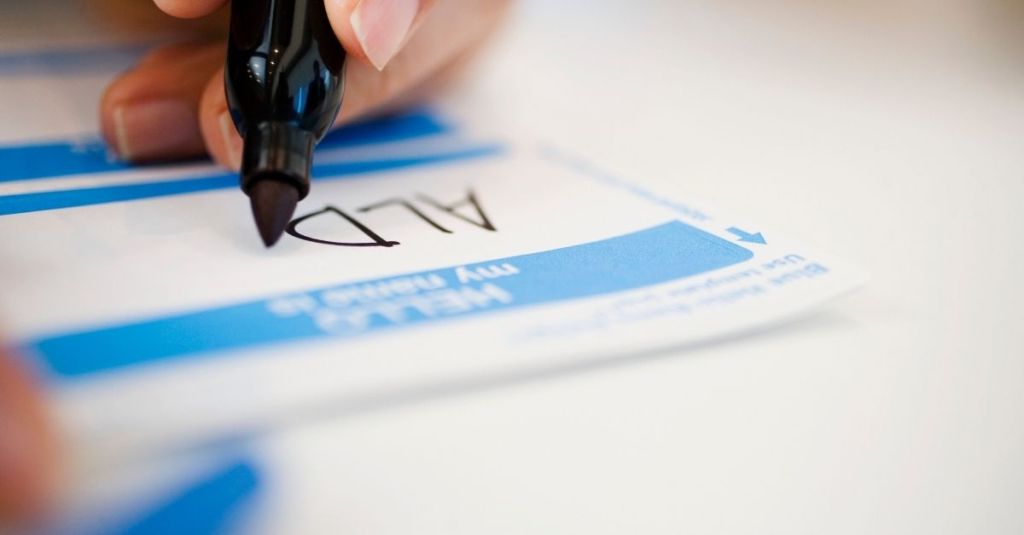 A person writing their name on a name badge with a marker