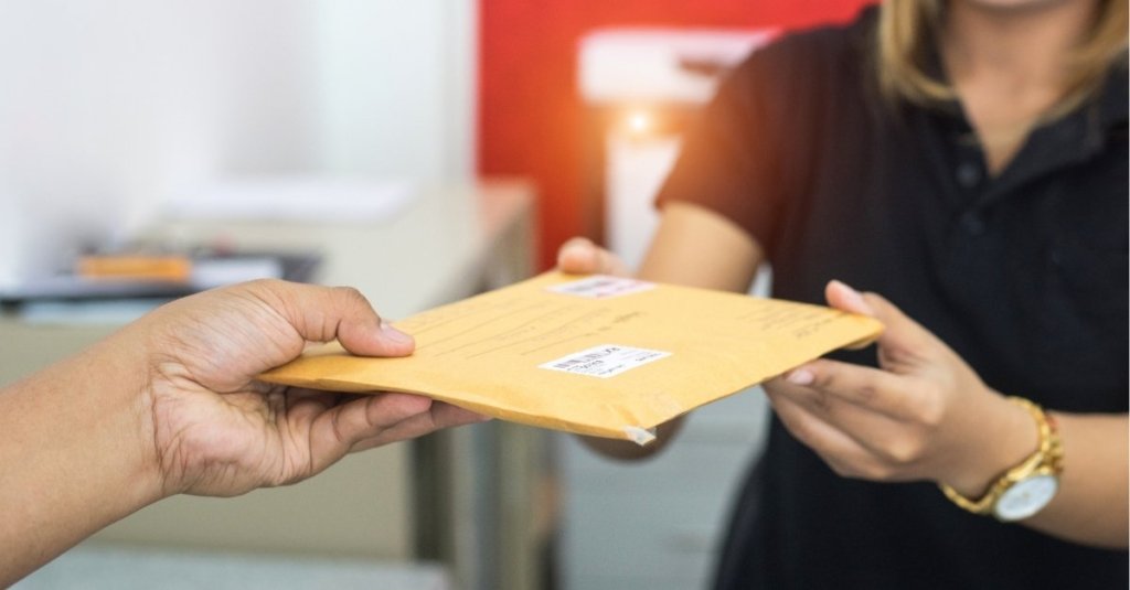 A man handing off an envelope to a woman