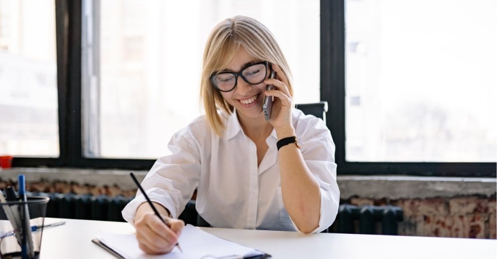 A woman taking notes while talking on the phone
