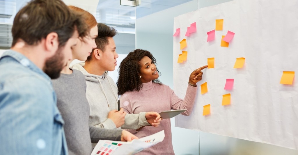 Woman pointing at a whiteboard with sticky notes
