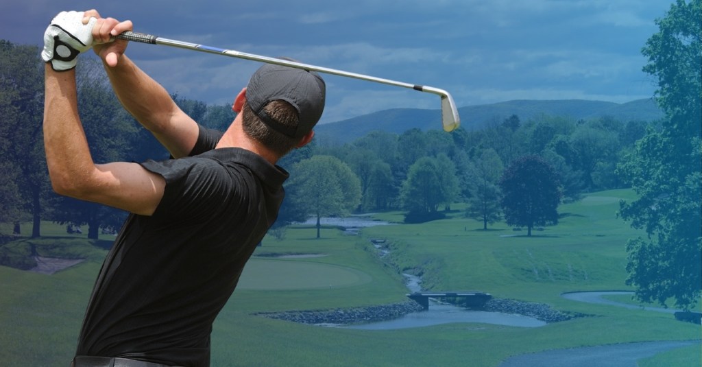 Man swinging golf club on a golf course.