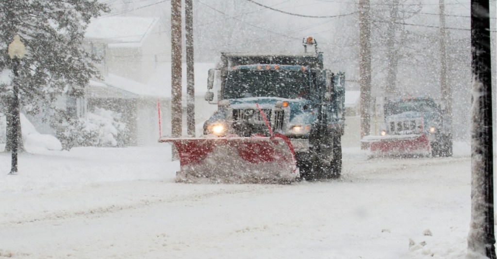 A snowplow plows the snow along a street