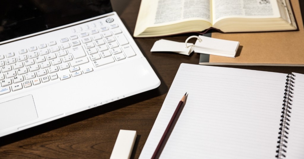A close-up view of a laptop, notepad, and book.