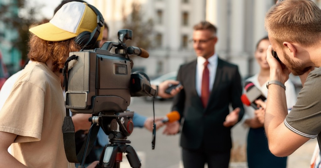 Horizontal shot of two operators recording and shooting an interview of a politician.