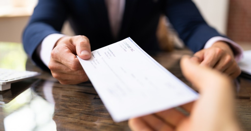 A man handing another person a check.