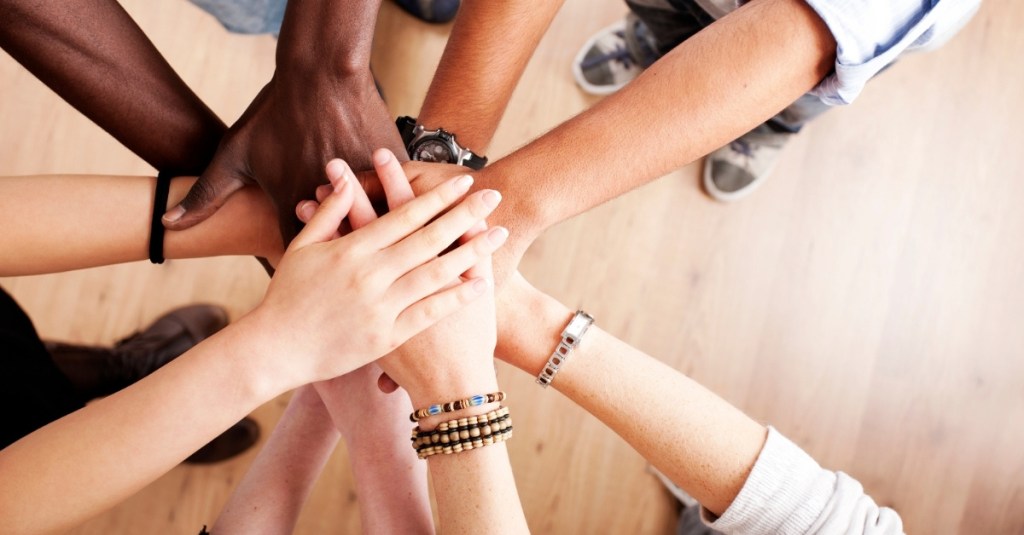 Group of people gathered together to put their hands in a circle.