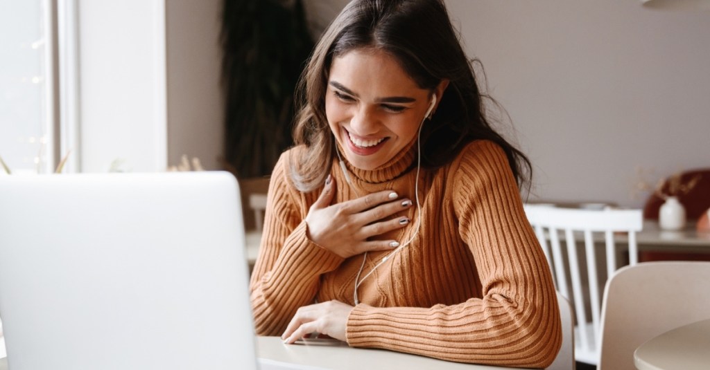 A girl laughing in a virtual meeting on a laptop.